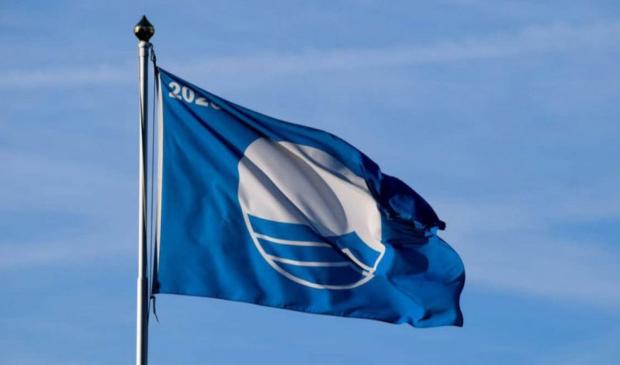 Blue flag waving in the wind, symbol of clean waters and safe beaches.